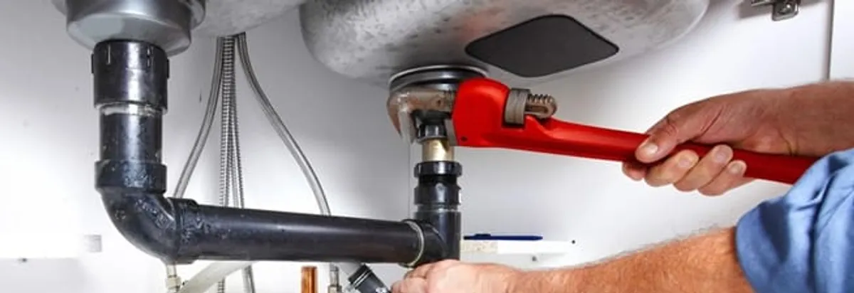 Garbage disposal repair technician tightening the sink drain and disposal connection in Pittsburgh, PA