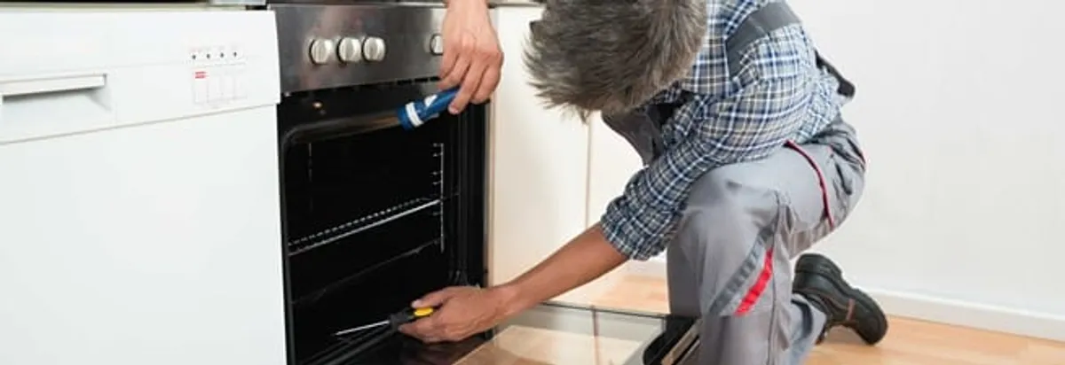 Oven repair technician inspecting and servicing an electric oven in Pittsburgh, PA