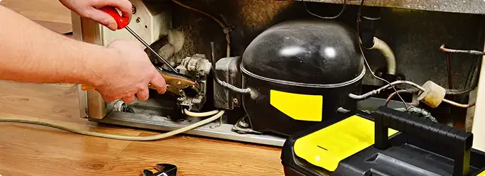 Refrigerator repair technician fixing the compressor and wiring in Pittsburgh, PA